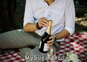 homem abrindo garrafa de champagnhe em piqnic 